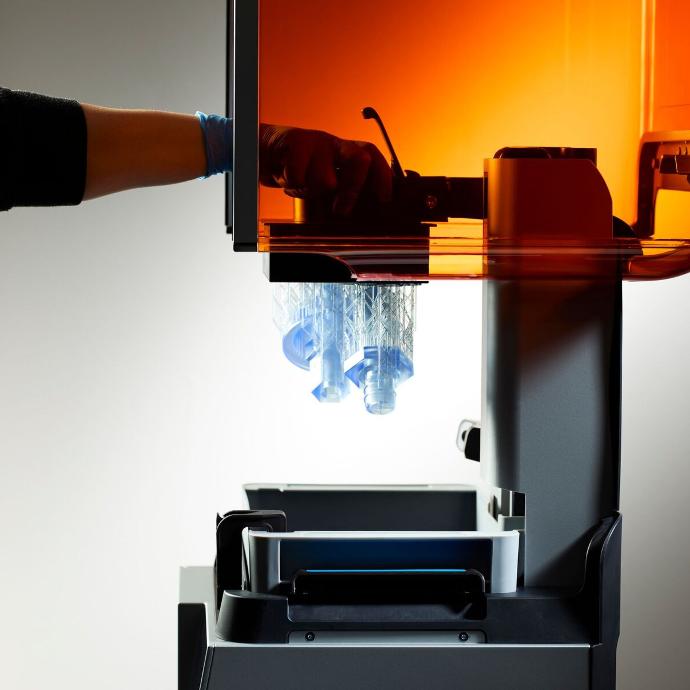 Resin 3D printer in operation with printed parts emerging from the build platform.